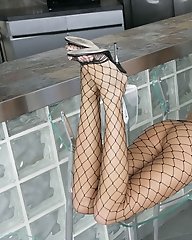 Layla Taylor posing in fishnet stockings by outdoor bar.